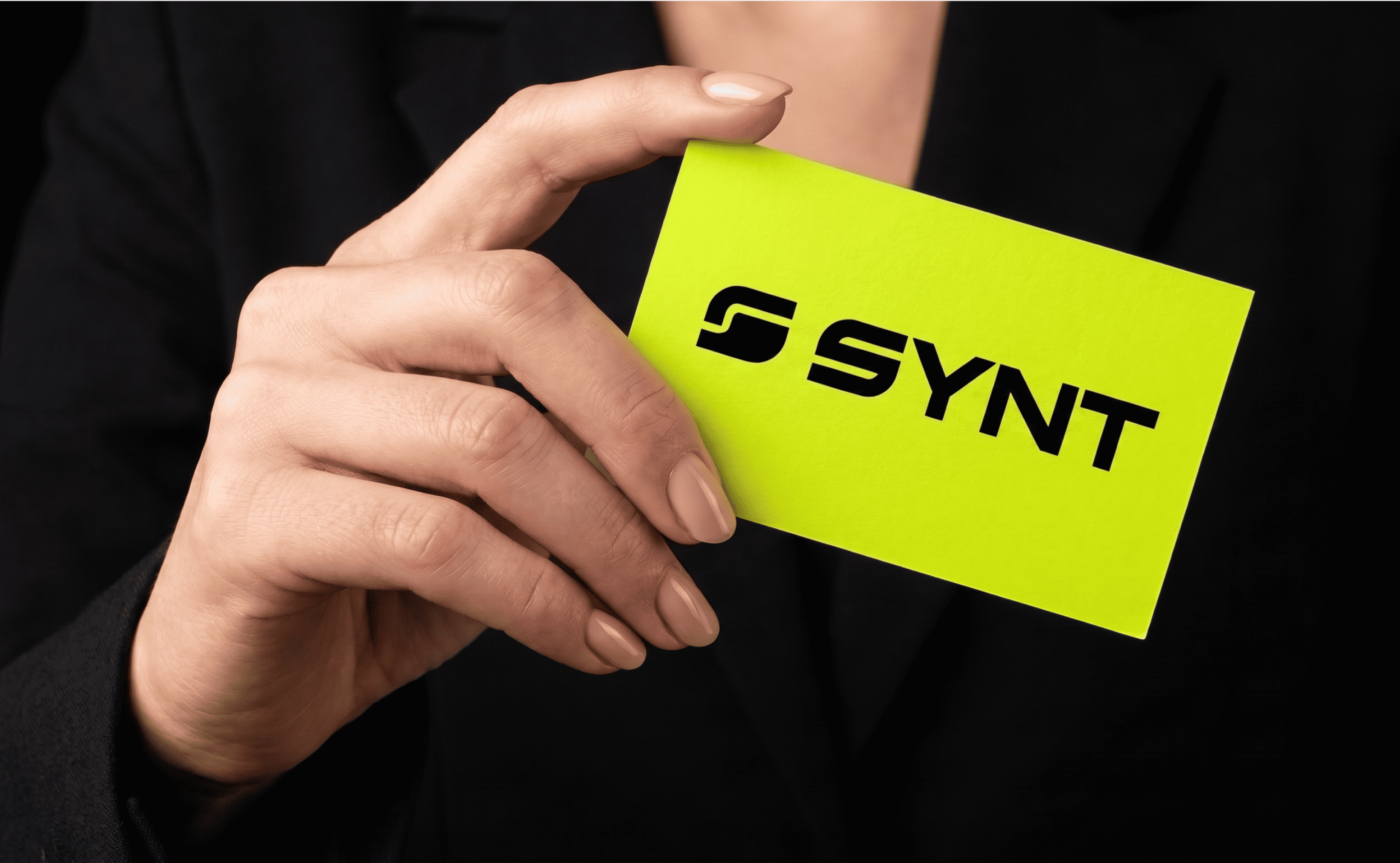 Hand holding SYNT branded business card in yellow and black